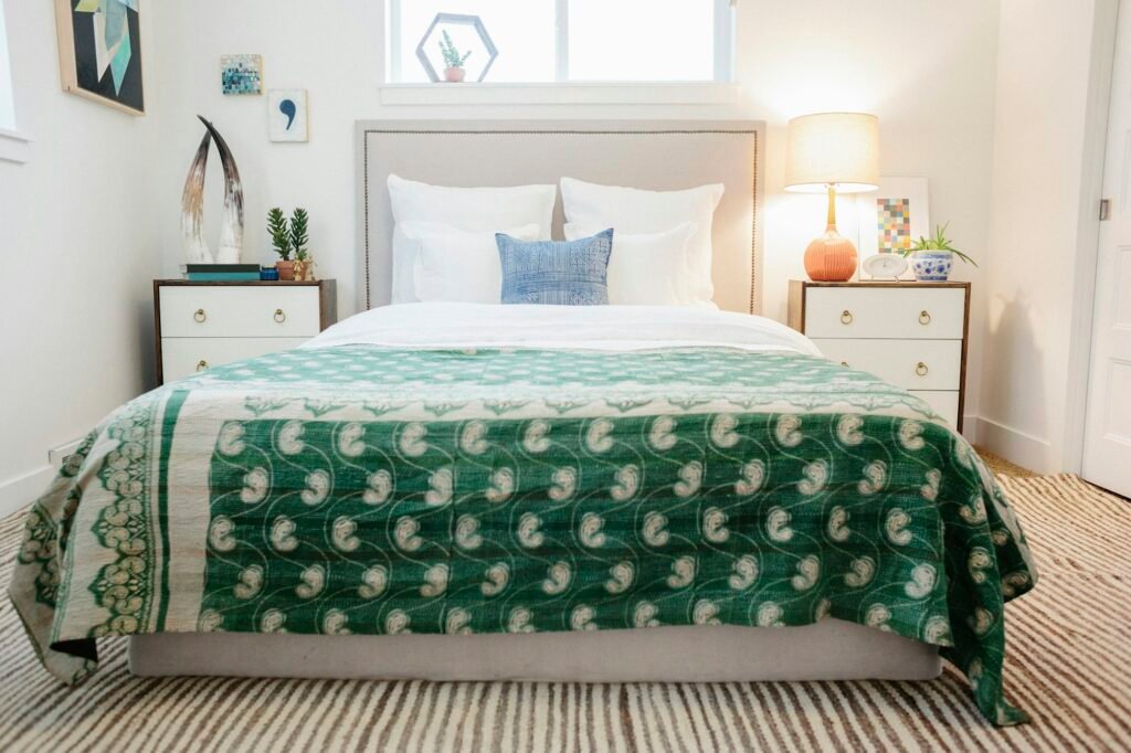 A bedroom in an apartment with a double bed and beside cabinets, and a green fabric patterned