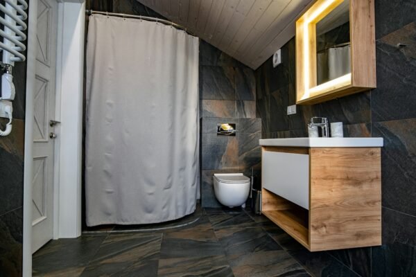 Interior of modern stylish bathroom with black tiled walls, curtain shower place